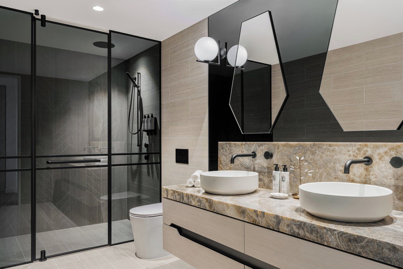 A modern bathroom with two sinks, a glass shower enclosure, and a large mirror.