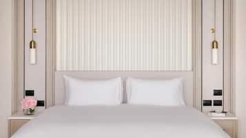 A hotel room with a large bed, two bedside tables, a nightstand, and a wall-mounted light fixture.