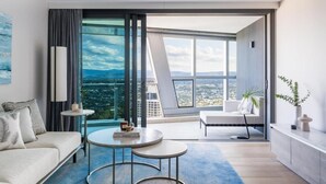 A modern living room with a sofa, two round tables, a balcony with a view of the city, and a large window. - The Langham, Gold Coast and Jewel Residences (Surfers Paradise)