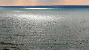 A beach with a calm sea and a cloudy sky.