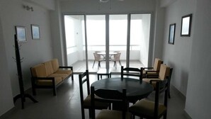 A spacious room with a round table and chairs, a sofa, and a balcony with a view.