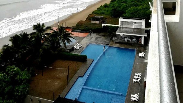 A high-rise building with a swimming pool and beach view.