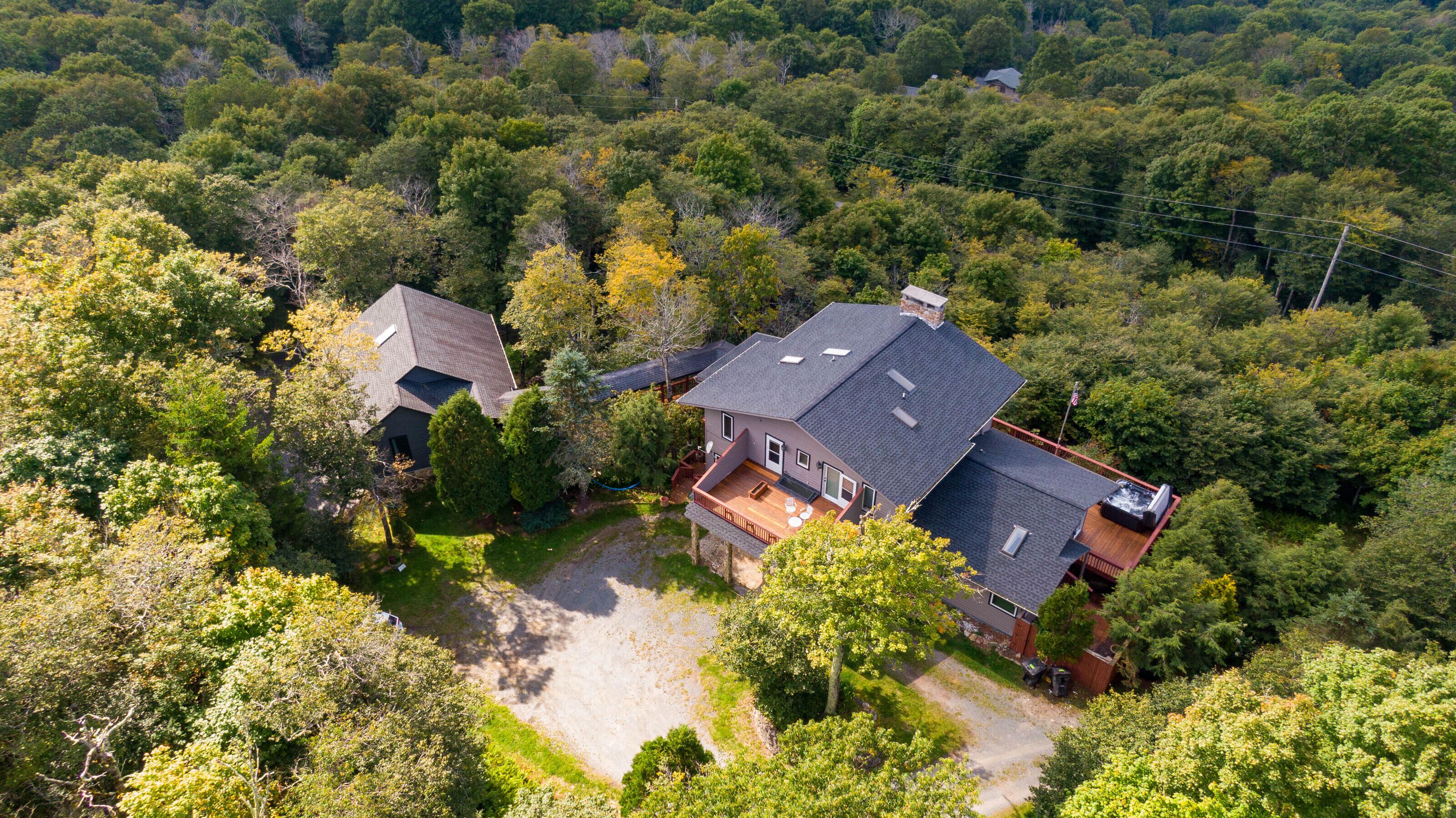 Una casa grande con una amplia terraza, rodeada de un bosque frondoso.