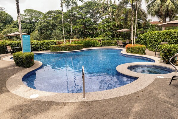 Une piscine au design incurvé, entourée d’une végétation bien entretenue et agrémentée de quelques chaises longues.