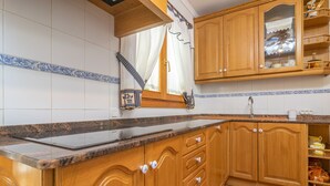 Cucina con mobili in legno, piano di lavoro in granito e finestra con tende.