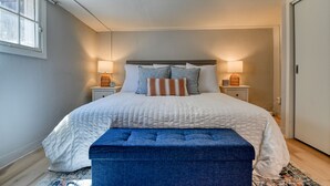 Un dormitorio con una cama grande, dos mesitas de noche con lámparas, una ventana y una puerta.