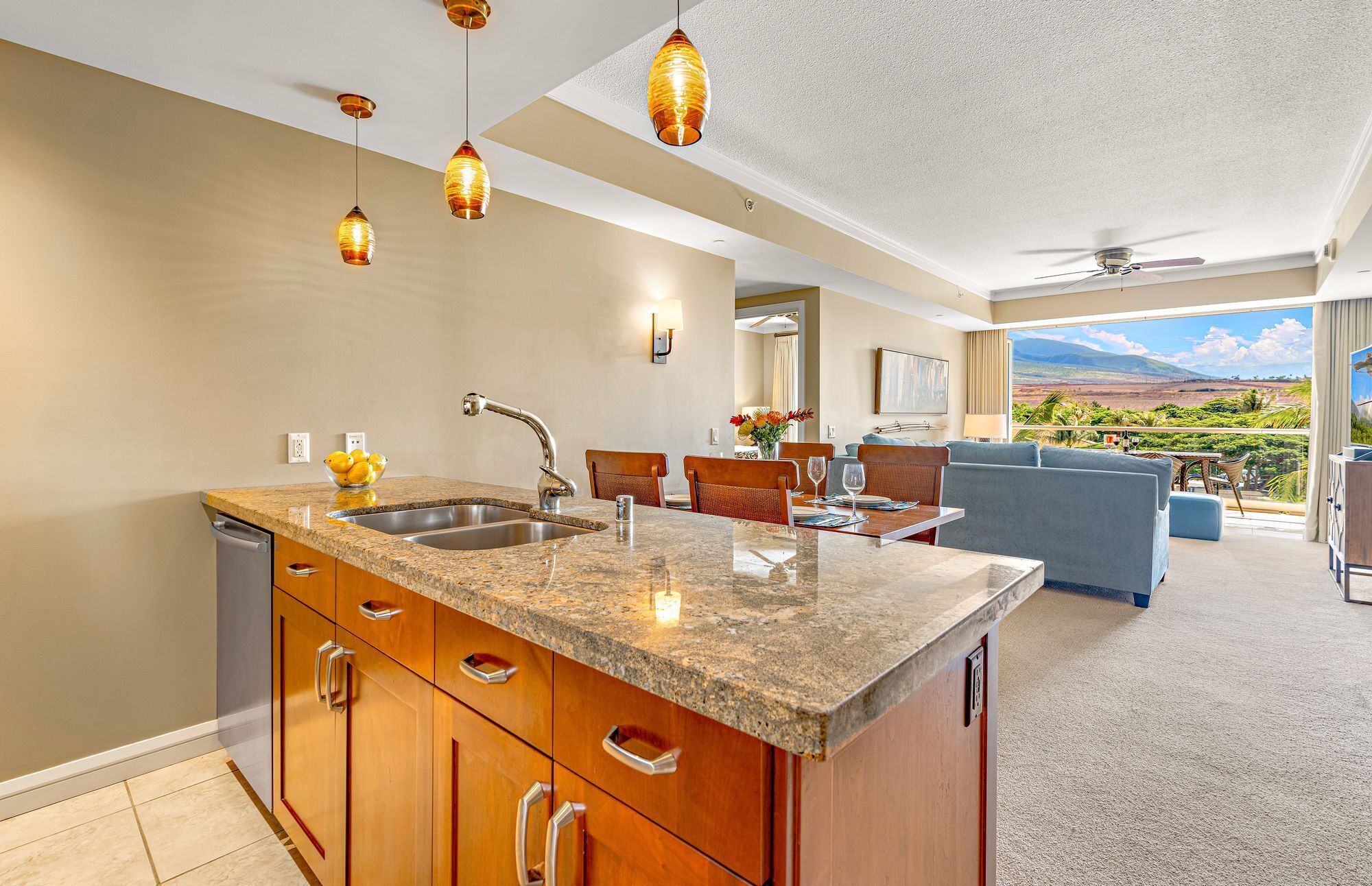 A modern kitchen with granite countertops, stainless steel appliances, and pendant lighting.