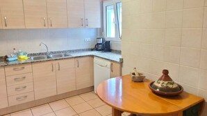 A kitchen with light wooden cabinets, a granite countertop, a coffee maker, and a Moroccan tagine on a wooden table. - Apartment ANDRES in the center of Els Poblets (Poblets (els))