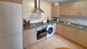 A compact kitchen with a Bosch washing machine, a microwave, and a built-in oven. - Apartment ANDRES in the center of Els Poblets (Poblets (els))
