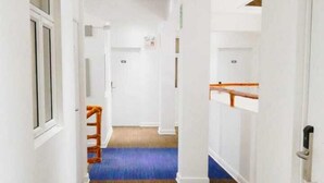 A hallway with wooden flooring, white walls, and a blue carpet.