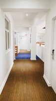 Un pasillo con piso de madera, paredes blancas y alfombra azul.