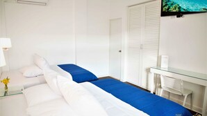 A hotel room with a bed, a desk, and a TV.