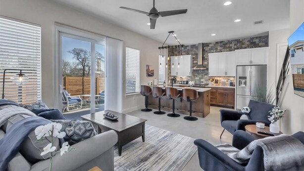 A modern kitchen with white cabinets, a stone backsplash, and a stainless steel refrigerator.