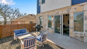 A patio with outdoor furniture, a barbecue grill, and a stone wall.