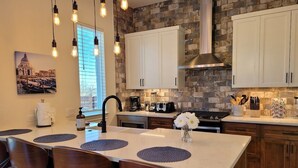 A modern kitchen with a central island, white cabinets, and a stone backsplash.