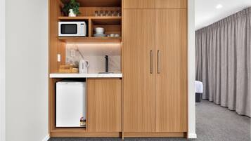 A compact kitchenette with a microwave, coffee maker, and storage cabinets.