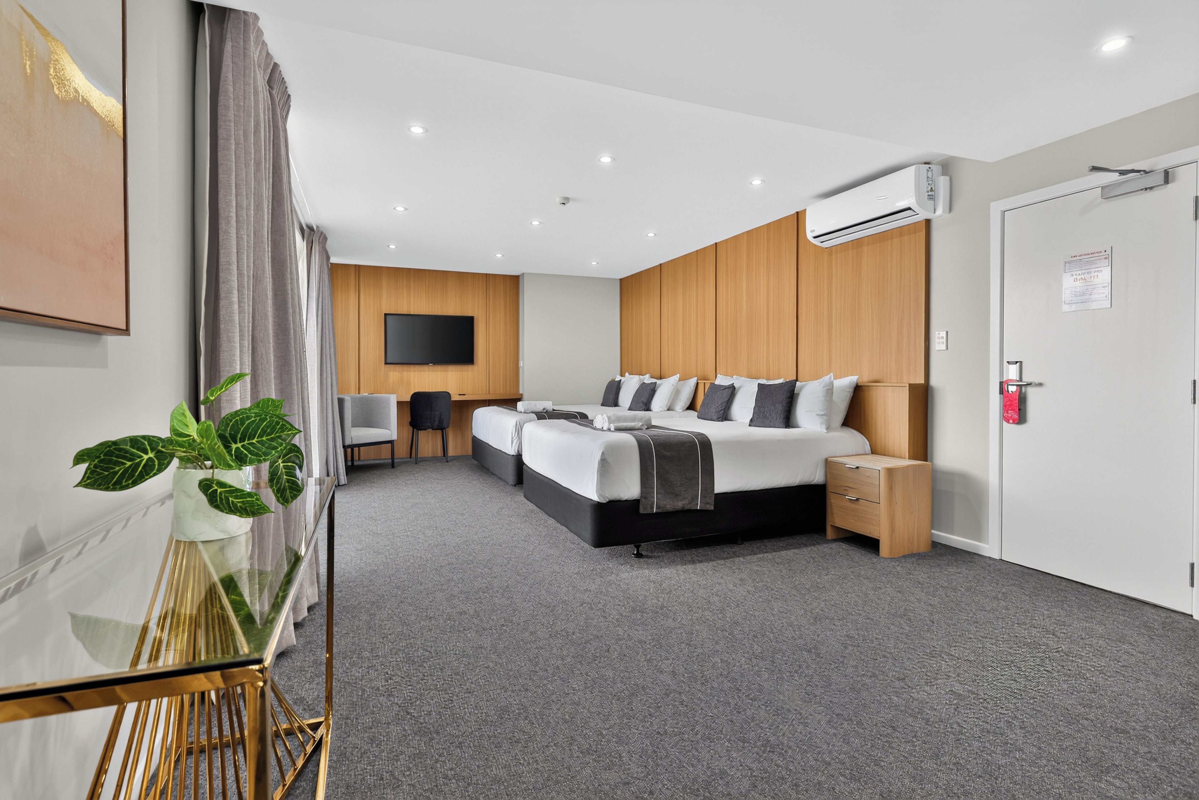 A modern hotel room with a large bed, a desk, and a television.