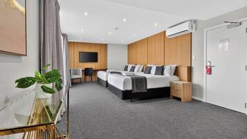 A modern hotel room with a large bed, a desk, and a television.