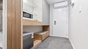 A compact kitchen with a microwave, refrigerator, and wooden counter.
