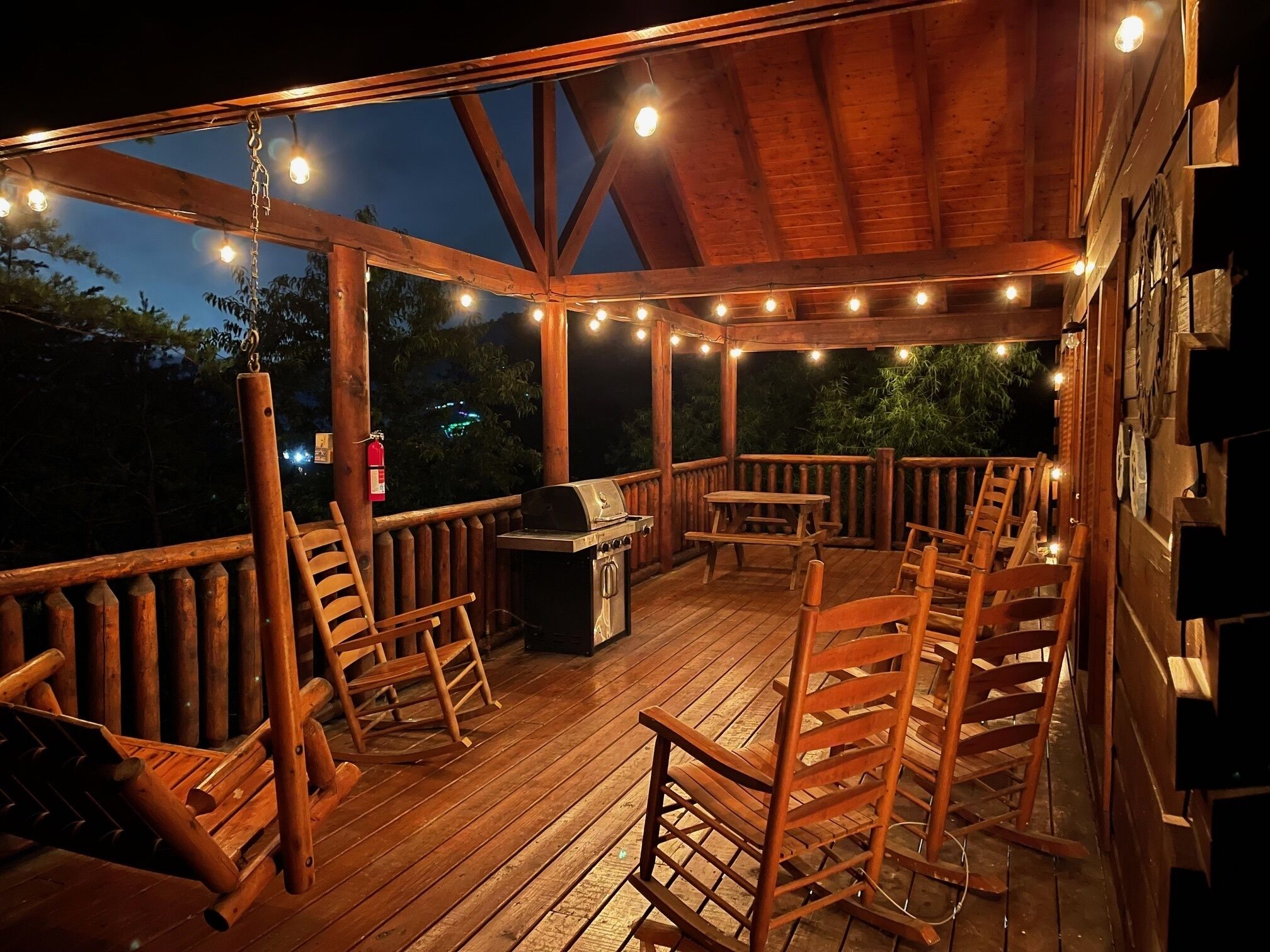 Een houten terras met een barbecue, stoelen en lichtjes.