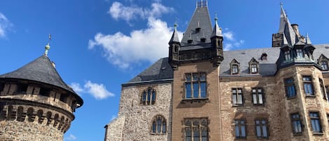 En historisk bygning med et rundt tårn, flere tårne og en markant indgang med buede vinduer.