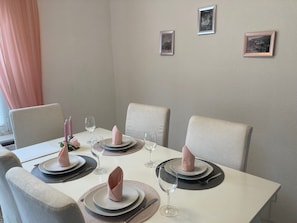 A dining table set with plates, napkins, and wine glasses, surrounded by chairs.