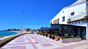 Ein Küstenweg mit einem Restaurant auf der rechten Seite, das Außenplätze und Pflanzkübel bietet.