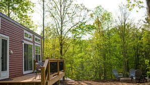 A cabin with a deck, surrounded by a forest. - Delightful Forest Tiny Home with Hot Tub (Murphy)