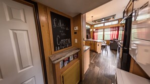 A cabin interior with a kitchen area, wooden walls, and a chalkboard with a quote. - Delightful Forest Tiny Home with Hot Tub (Murphy)