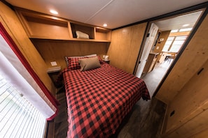 Une petite chambre comprenant un lit, une table de chevet et une tête de lit en bois.