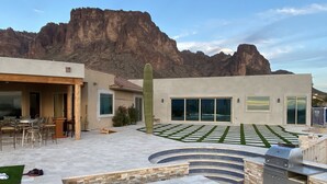 An outdoor patio with a grill, seating area, and a cactus. - Beautiful oasis with 40' negative edge pool, swim up bar, hiking in Super. Mtns. (Apache Junction)