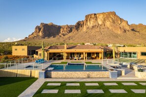Une maison moderne dotée d’une piscine, d’un espace salon extérieur et offrant une vue sur une montagne.