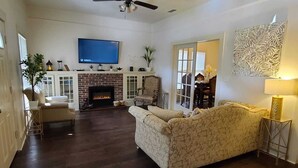 A living room with a fireplace, a television mounted on the wall, and a ceiling fan. - Beautiful 3BR&2BA House located in the Historic part of Brownville-SPI-SpaceX-MX (Brownsville)