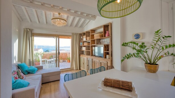 Un salon moderne avec un canapé, une table à manger et des chaises. Il y a un balcon avec vue sur la ville.