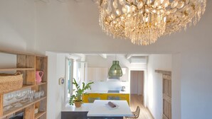 Une cuisine moderne dotée d’un îlot central, d’étagères en bois et d’un lustre.