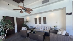 A lobby with wicker furniture, ceiling fans, and potted plants. - Resort Style Condo near Disneyland, Beaches, Los Angeles & so much more  (Fountain Valley)