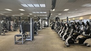 A gym with various exercise machines, including treadmills and weight machines, arranged in rows. - Resort Style Condo near Disneyland, Beaches, Los Angeles & so much more  (Fountain Valley)