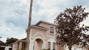 A two-story house with a beige facade, white trim, and arched windows.