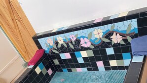 Une piscine carrelée avec un motif géométrique et une mosaïque florale sur le mur.
