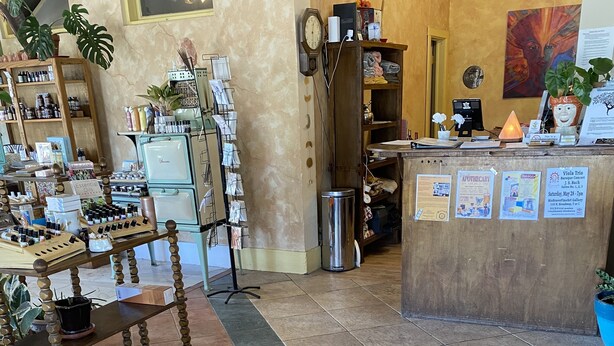 Le hall d’un hôtel-boutique doté d’un sol carrelé, d’un comptoir d’accueil en bois et de diverses commodités, notamment une machine à café, une horloge et une plante.