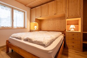 Une chambre à coucher avec un lit en bois, deux lampes de chevet et des armoires encastrées en bois.