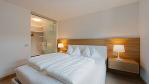 Une chambre d’hôtel comprenant un lit, des tables de chevet, une commode, un miroir et une armoire.