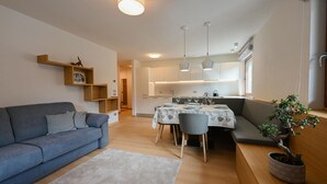 Un salon moderne avec un canapé, une table à manger dressée pour quatre personnes et une cuisine en arrière-plan.