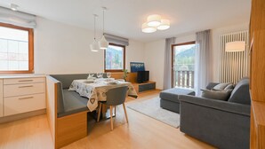 Un salon moderne avec un canapé, une table à manger dressée pour deux personnes et un téléviseur.