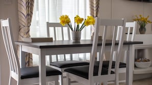 Ein Esstisch mit weißen Stühlen und einer Vase mit gelben Blumen.