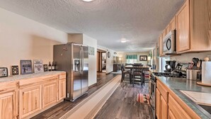 Eine moderne Küche mit Holzausbau, einem Edelstahlkühlschrank und einem Essbereich mit Tisch und Stühlen.