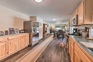 A modern kitchen with wooden cabinets, a stainless steel refrigerator, and a dining area with a table and chairs.