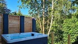 A hot tub with a wooden deck and steps, surrounded by a wooden fence and trees. - Fantastic chalet with outdoor WHIRLPOOL. NEW since 2024: outdoor SAUNA!!! (Gersfeld (Rhön))