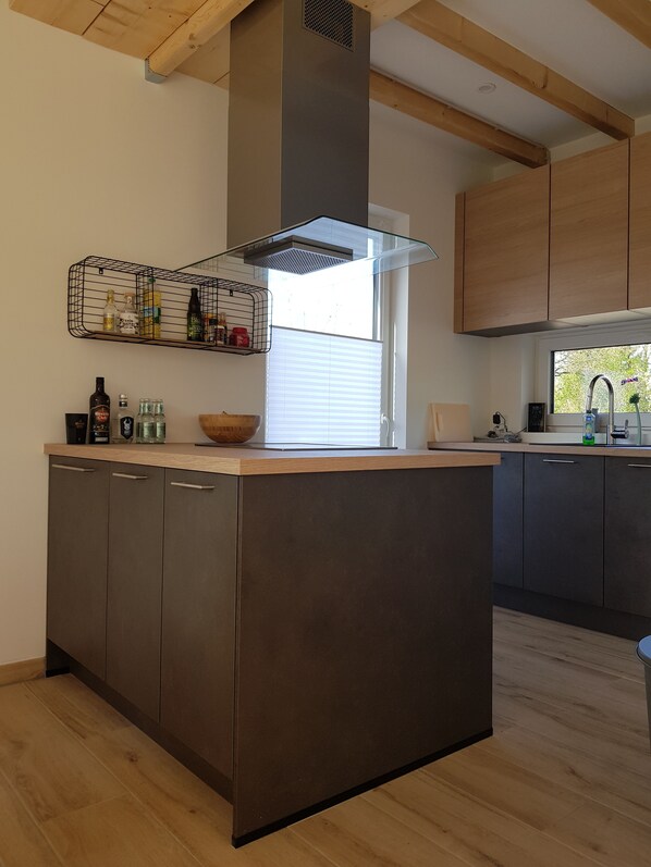 A modern kitchen with a central island, wooden cabinets, and a built-in range hood.
