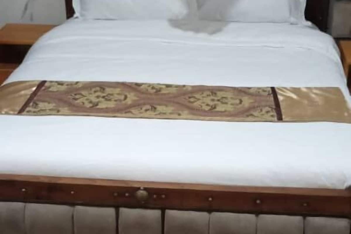 Un lit avec une tête de lit en bois, une literie blanche et une couvre-lit à motifs.